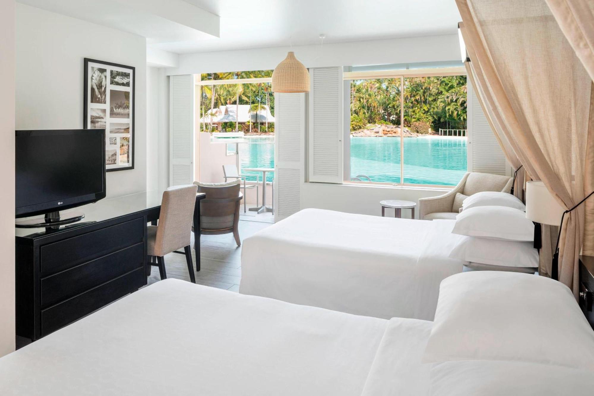 Zimmer mit zwei Doppelbetten, Zugang zum Pool und Zugang zur kleinen Lagune